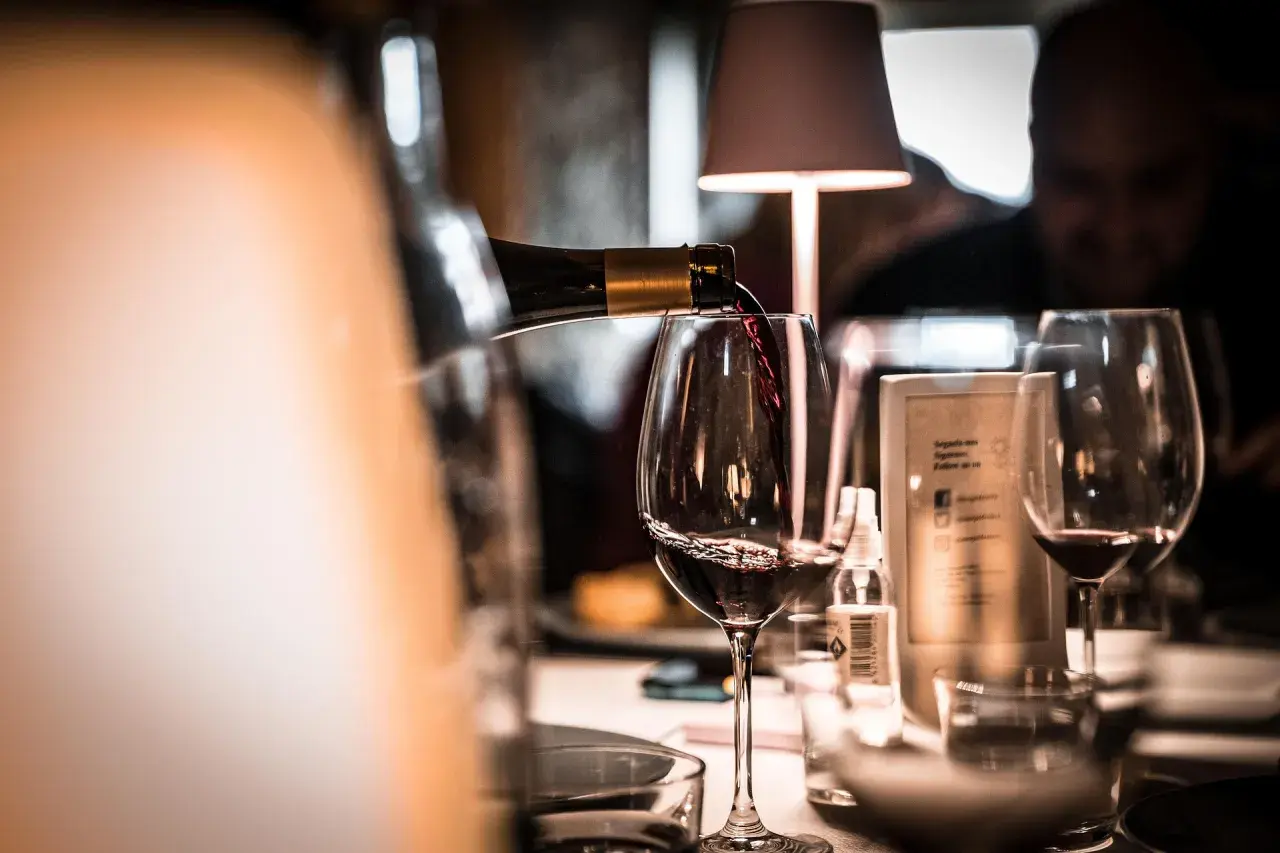 Verre de vin rouge servi dans un bar, ambiance feutrée.