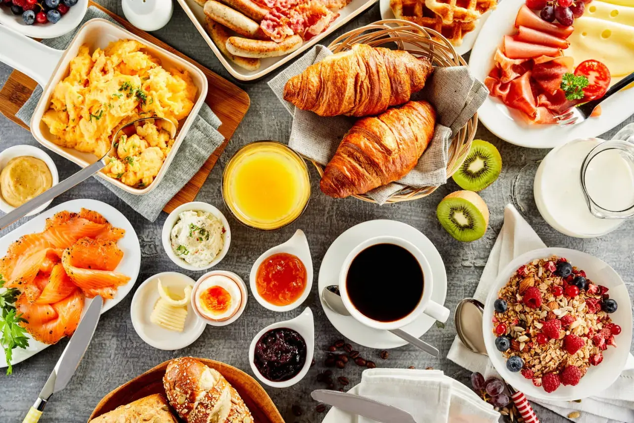 Un festin pour un brunch mariage : œufs brouillés, saumon fumé, croissants, fruits, café et granola.