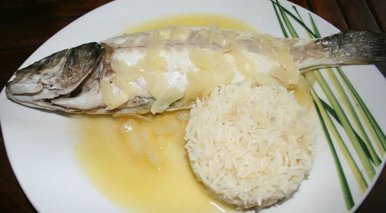 Un délicieux filet de loup au four, nappé d'une sauce au vin blanc et accompagné de riz.