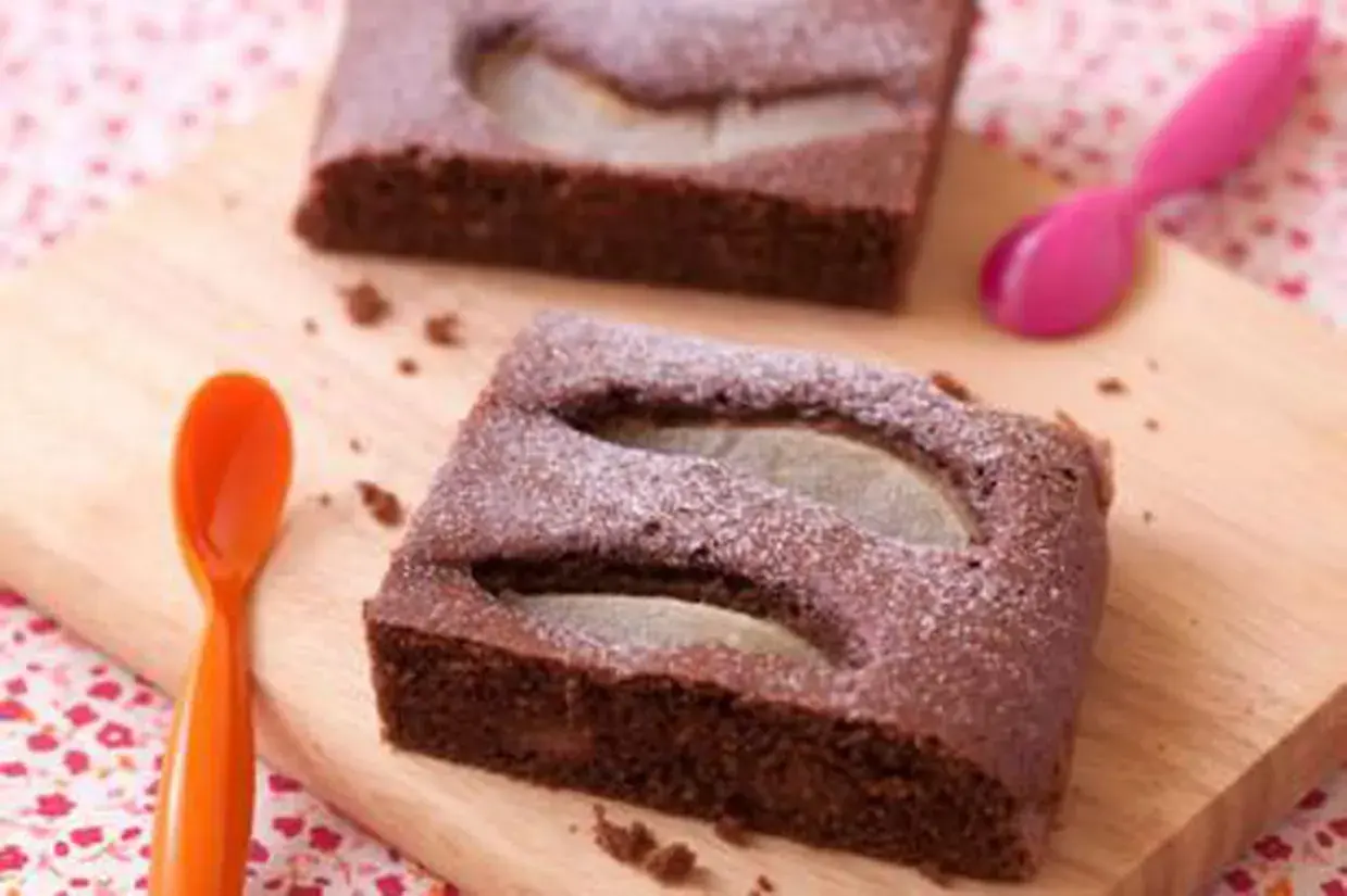 Gâteau au chocolat et poire, saupoudré de sucre glace. Une idée pour apporter un dessert original et gourmand.