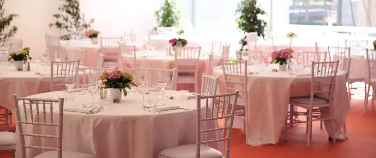 Tables dressées pour un mariage sans traiteur, avec des chaises blanches et des centres de table floraux.