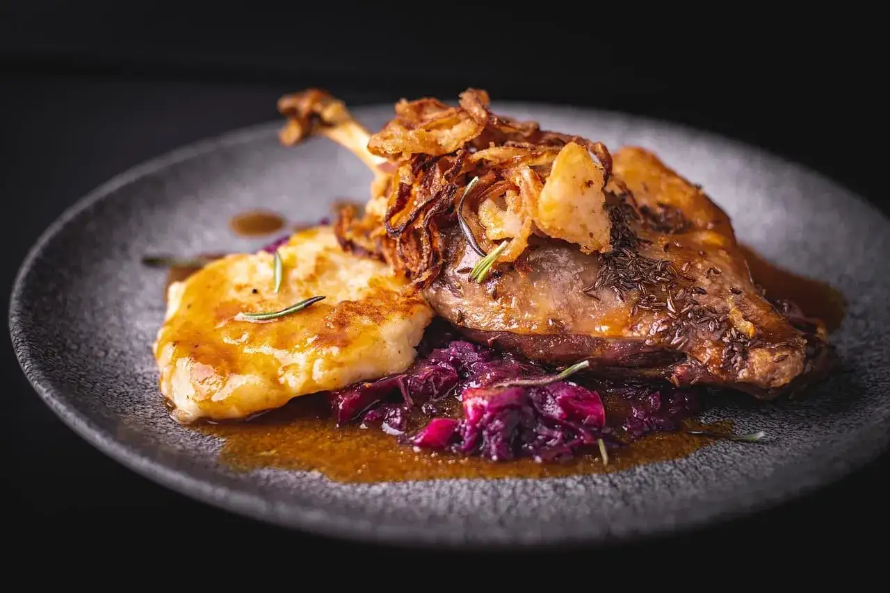 Un plat de canette r&ocirc;ti, garni d'oignons frits croustillants, servi avec une pur&eacute;e dor&eacute;e et du chou rouge. Un accompagnement canette parfait pour un repas savoureux.