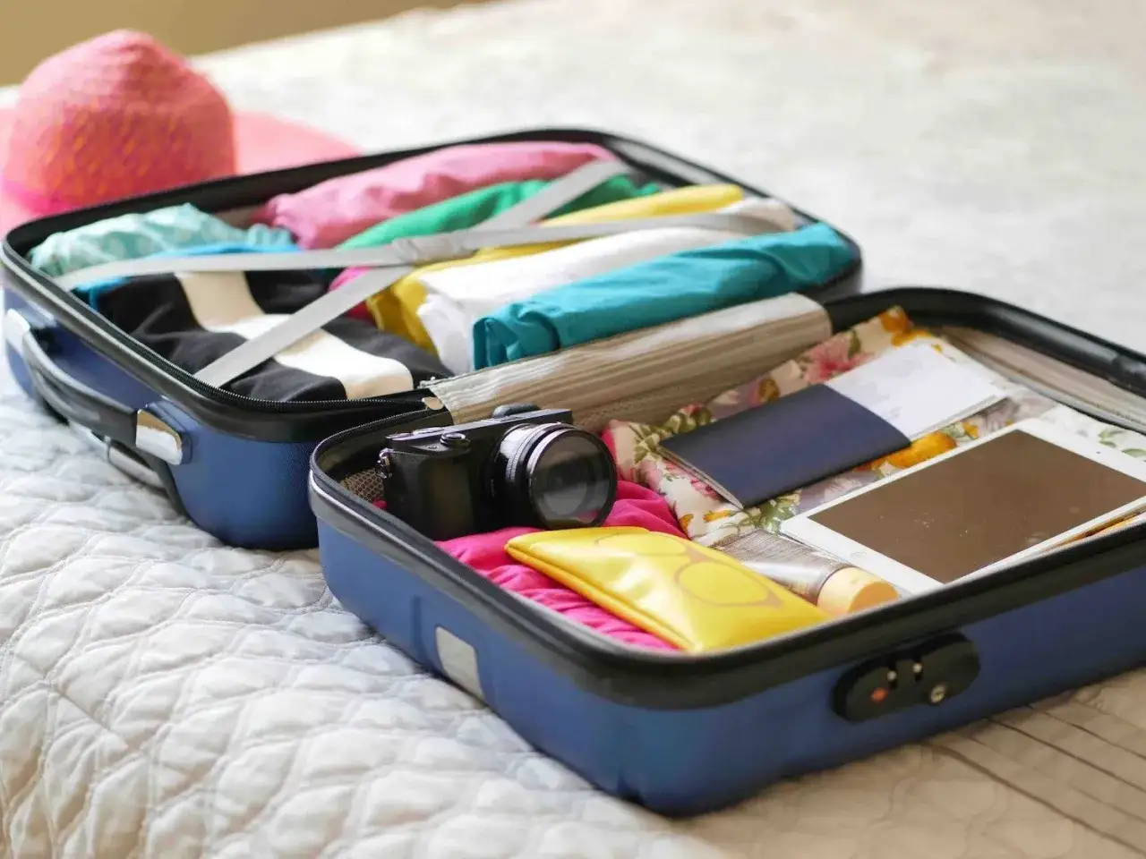 Valise ouverte pr&ecirc;te pour un EVJF : v&ecirc;tements color&eacute;s, appareil photo, tablette, passeport. Une liste valise EVJF dr&ocirc;le pour un voyage inoubliable !