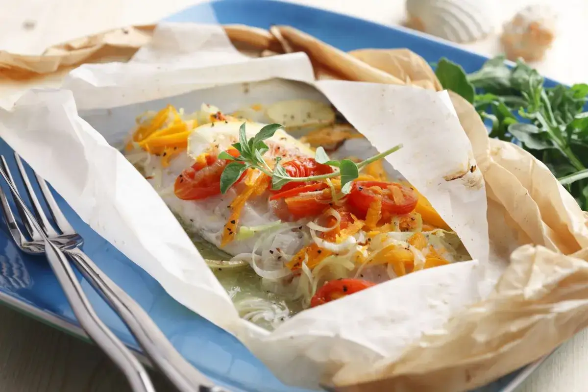 Poisson blanc cuit en papillote avec tomates et légumes. Un plat léger, parfait pour savoir quel vin avec du cabillaud.