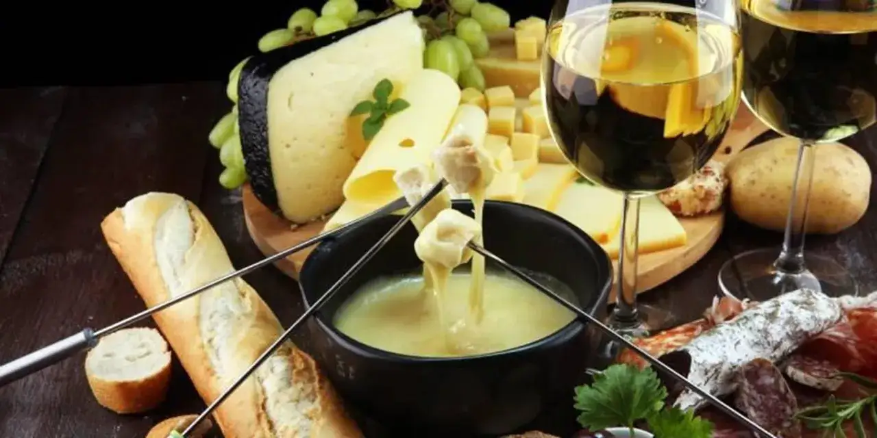 Un délice de fondue suisse avec pain, fromages variés, charcuterie et un verre de vin pour fondue suisse.