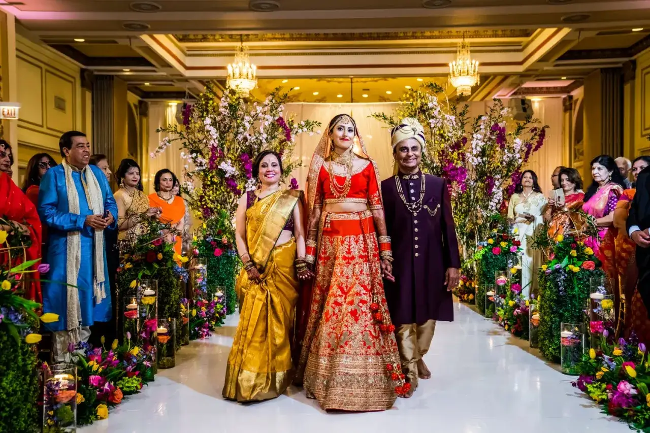 La mari&eacute;e, accompagn&eacute;e de ses parents, rayonne dans une tenue &eacute;clatante, un moment digne d'un mariage Bollywood.