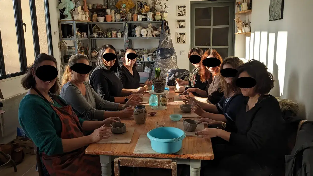 Des femmes participent &agrave; un atelier EVJF de poterie, cr&eacute;ant des objets en argile dans une ambiance conviviale.