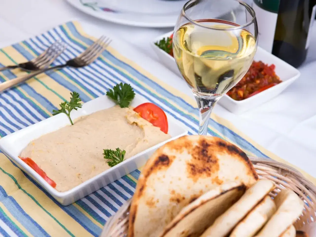 Un verre de sauvignon blanc avec du houmous, du pain pita et une sauce épicée. Parfait pour un apéritif.
