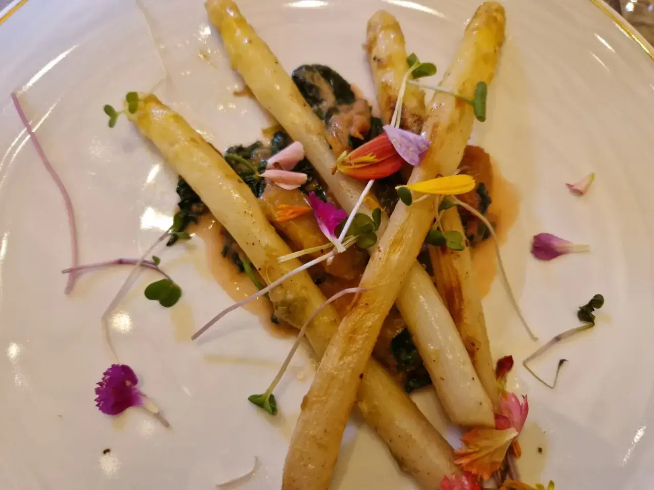Asperges blanches sur lit de verdure, parsemées de fleurs comestibles. Une belle idée de ce que manger avec du Sauternes pour un accord parfait.