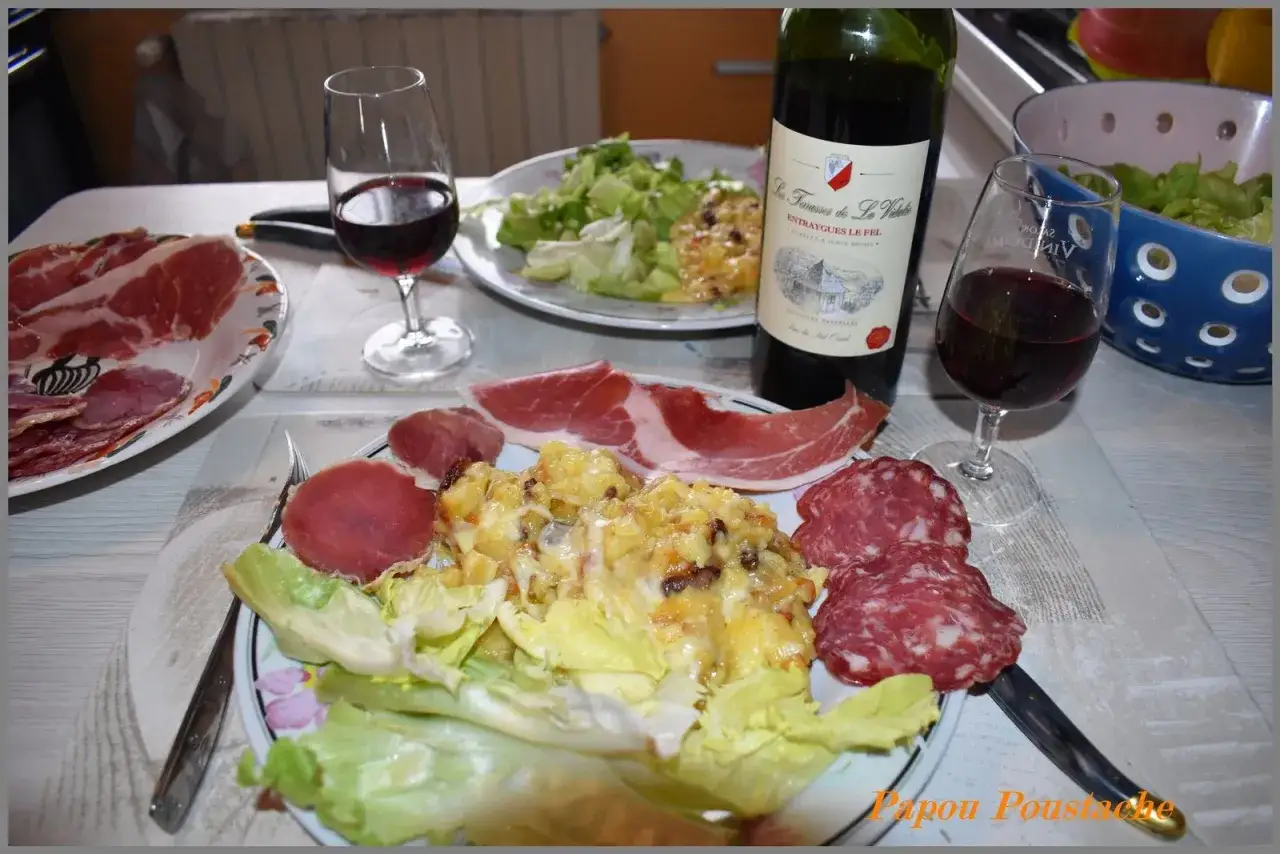 Un repas convivial avec un vin rouge et une truffade généreuse, accompagnée de charcuterie et de salade.