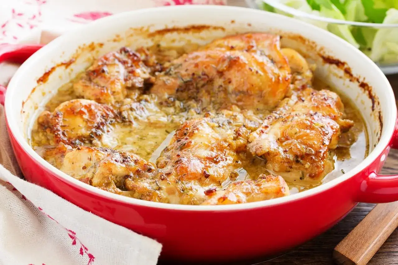Poulet r&ocirc;ti dans un plat rouge, sauce cr&eacute;meuse aux herbes. Un d&eacute;lice pour le repas du week-end.
