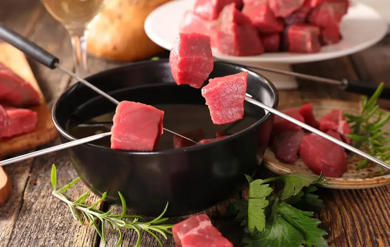 Des cubes de bœuf sur des brochettes prêts à être plongés dans l'huile chaude pour une fondue bourguignonne. Quel vin pour une fondue bourguignonne ?