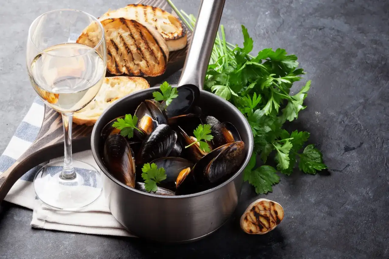 Moules marinières avec pain grillé et un verre de vin blanc. Quel vin d'Alsace avec des moules ? Un Riesling frais serait parfait.