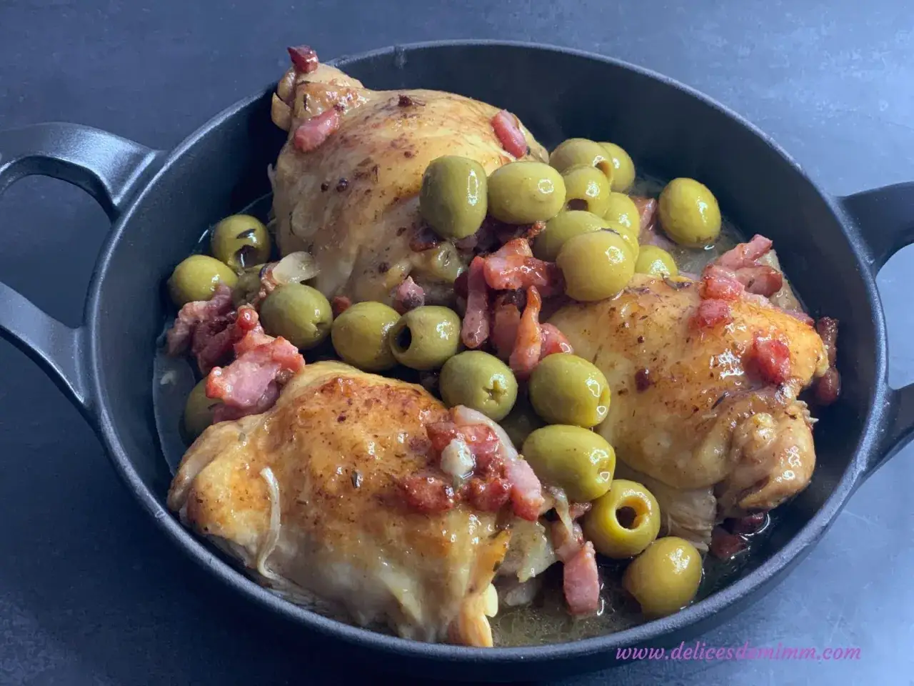Un plat de poulet calvi, avec des morceaux de poulet dorés, des olives vertes et des lardons, mijotant dans une sauce savoureuse.