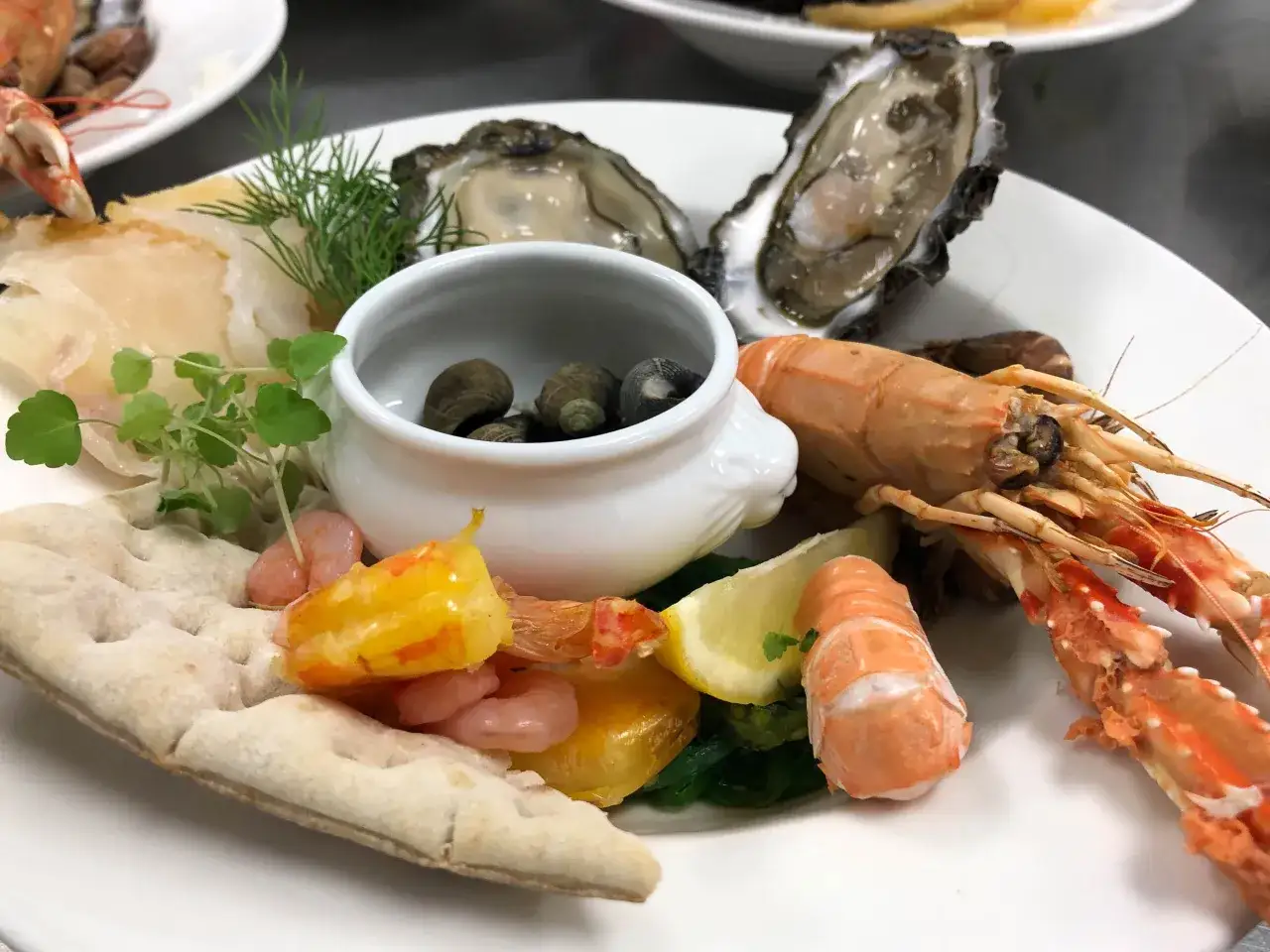Une assiette de fruits de mer pour une personne : hu&icirc;tres, crevettes, langoustines, coquillages et pain.