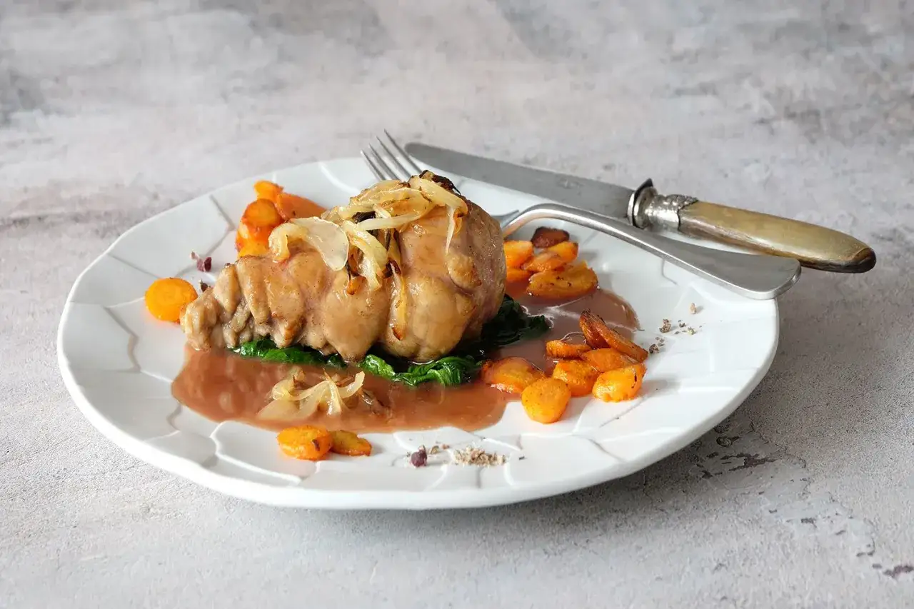 Un plat de ris de veau braisé, nappé d'une sauce onctueuse, accompagné de carottes croquantes et d'une touche d'oignons caramélisés. Un délice à savourer avec un bon vin.