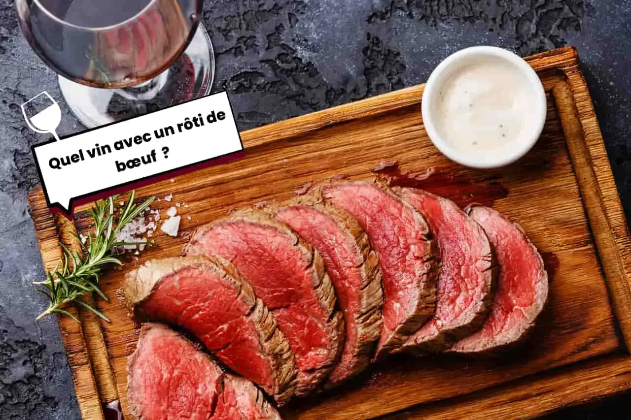 Un verre de vin rouge accompagne un délicieux rôti de bœuf tranché, servi sur une planche en bois avec une sauce crémeuse.