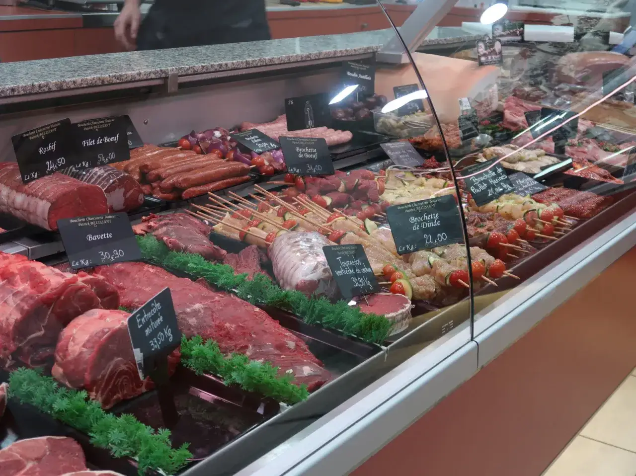 Vitrine de boucherie regorgeant de viandes fra&icirc;ches, brochettes et saucisses. Une belle id&eacute;e pr&eacute;paration boucherie pour un repas savoureux.