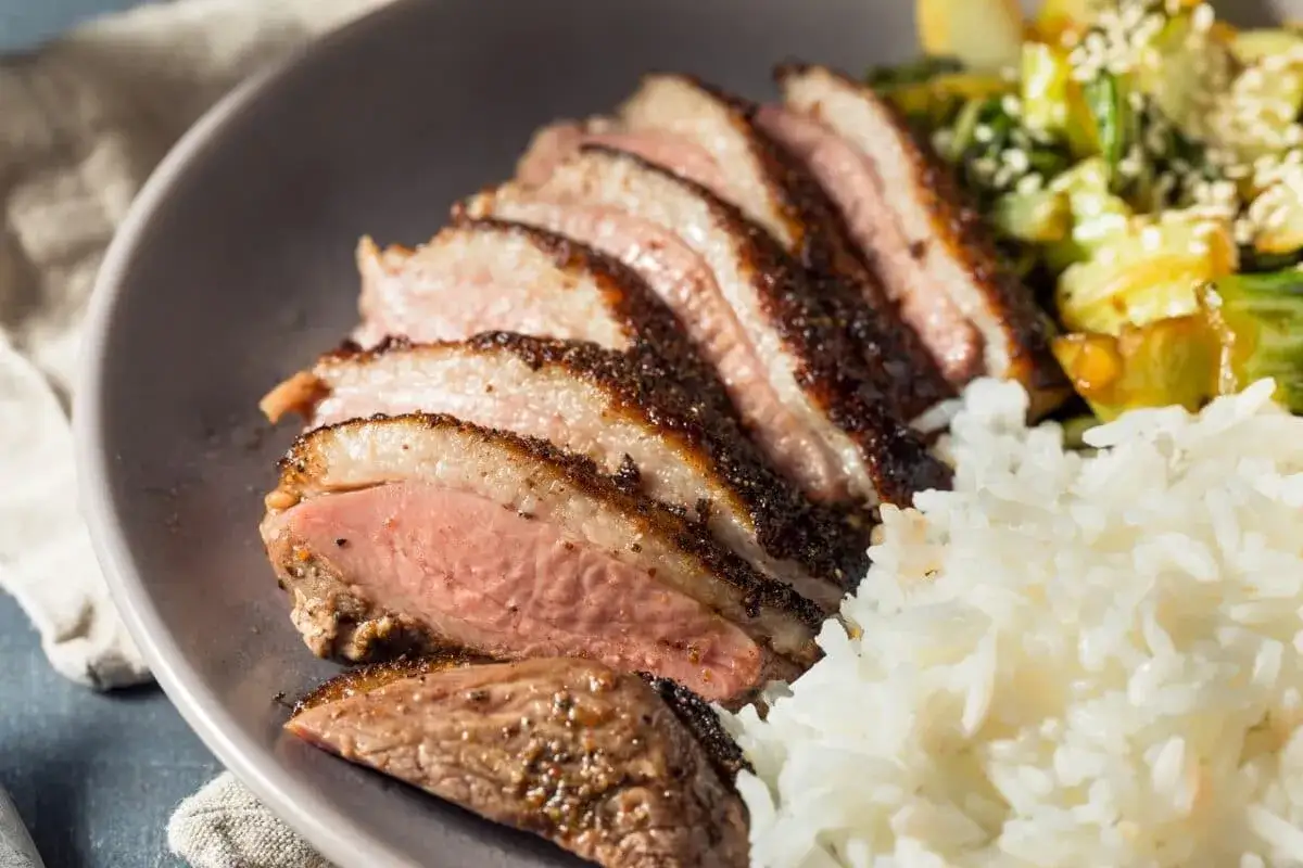 Tranches de magret de canard juteux, accompagnées de riz blanc et d'une poêlée de légumes. Un délice à savourer avec un verre de vin blanc.
