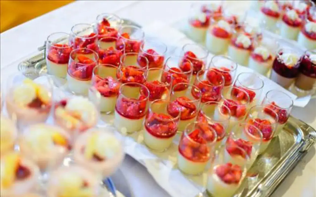 Plateau de mini dessert pour buffet : verrines cr&eacute;meuses garnies de fraises fra&icirc;ches et de coulis rouge.