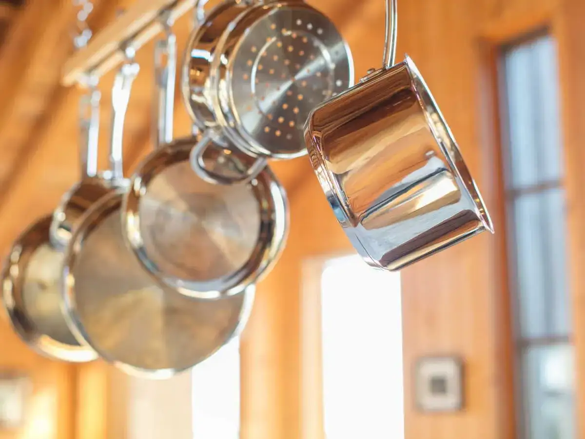 Casseroles en inox suspendues. Une astuce pour savoir comment enlever le caramel d'une casserole est de la faire tremper dans de l'eau chaude avec du bicarbonate de soude.