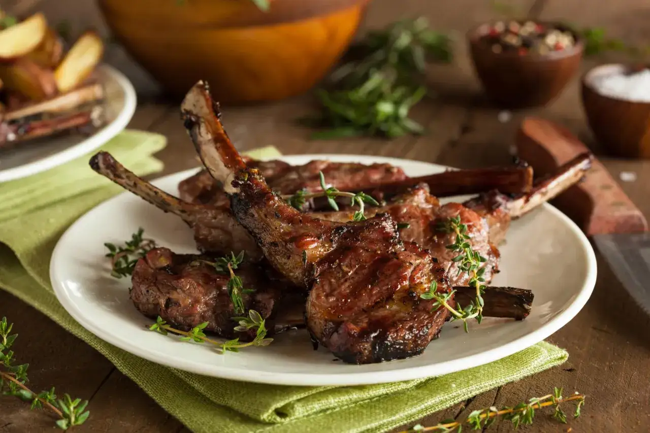 Délicieuses côtes d'agneau grillées, garnies de thym frais. Un plat parfait pour se demander quel vin boire avec des côtes d'agneau grillées.