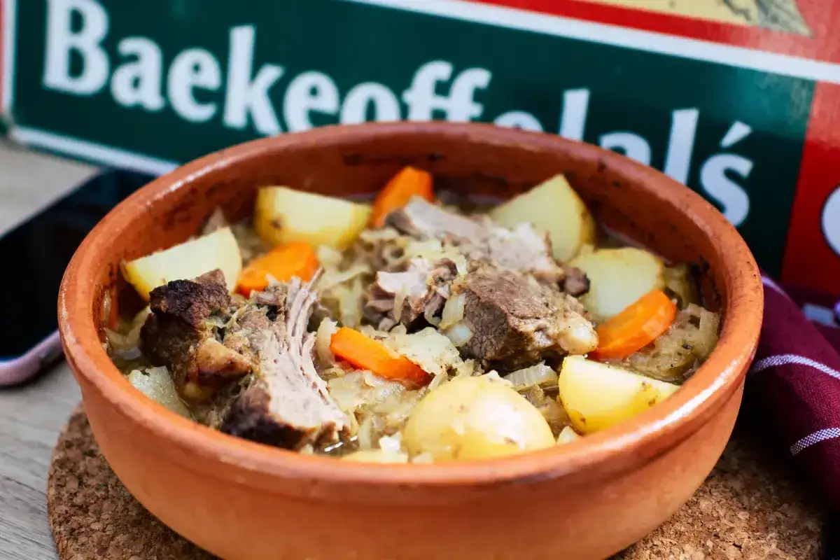 Un plat de baeckeoffe mijoté dans une cocotte en terre cuite, avec des morceaux de viande, des pommes de terre et des carottes. Quel vin avec baeckeoffe ?