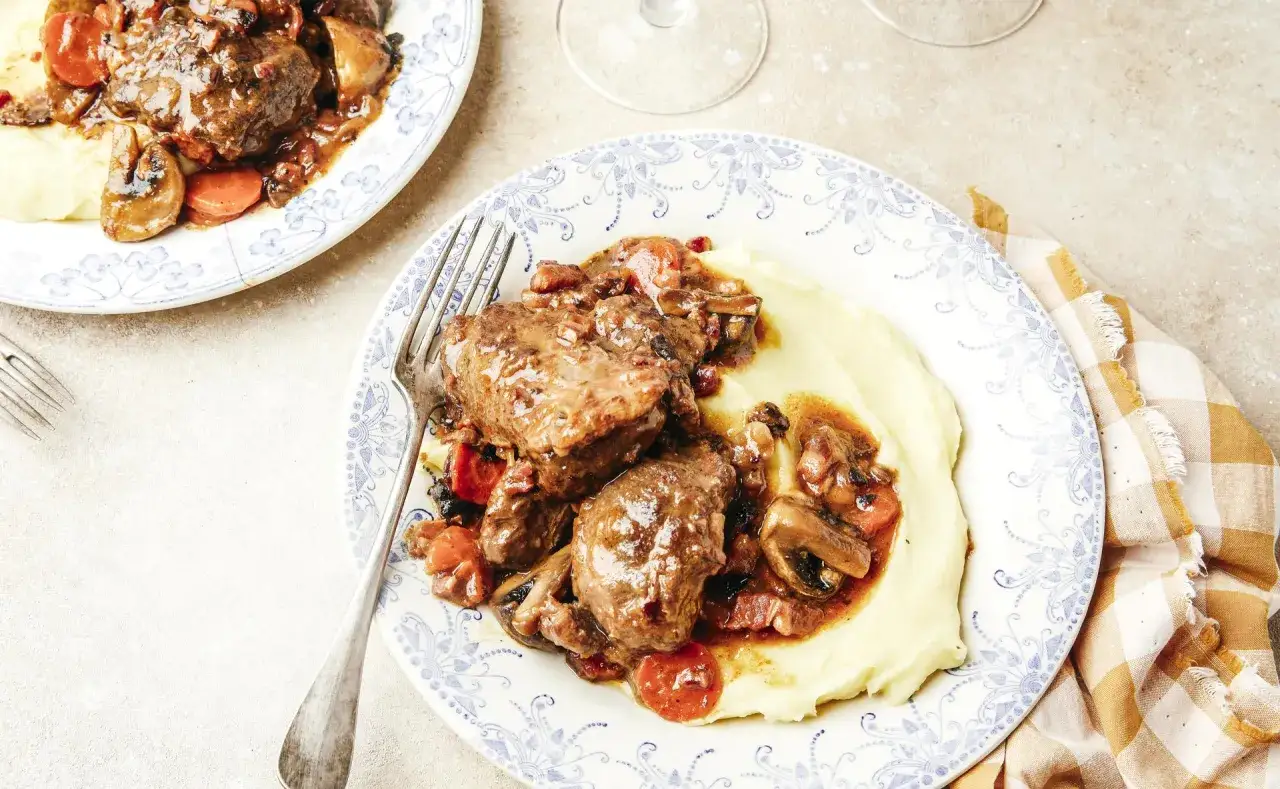 Joue de porc au cidre, champignons et carottes, servie sur une purée onctueuse. Quel vin avec joue de porc au cidre ? Un cidre brut ou un vin rouge léger.
