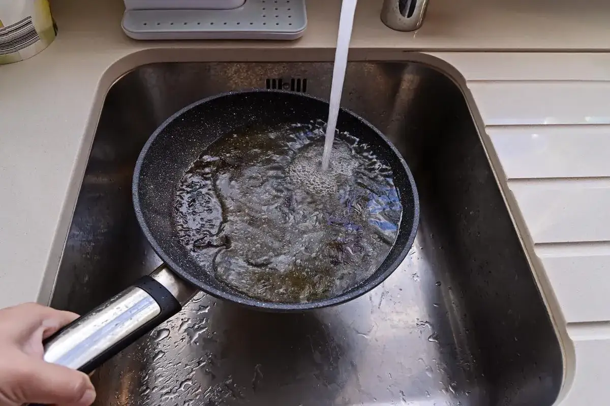Une po&ecirc;le sale sous l'eau courante. Une m&eacute;thode pour comment enlever une tache de brulure.