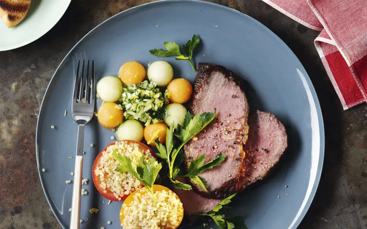 Tranches de rosbeef froid, accompagn&eacute;es de billes de melon, de tomates farcies au quinoa et de persil frais. Un plat l&eacute;ger et color&eacute;.