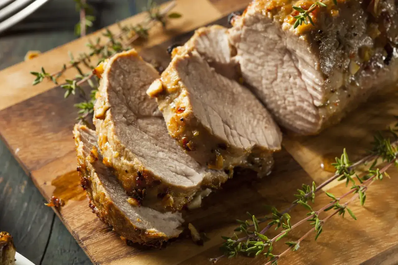 Tranches de filet mignon ros&eacute;, juteux et savoureux, sur une planche en bois, garni de thym frais.