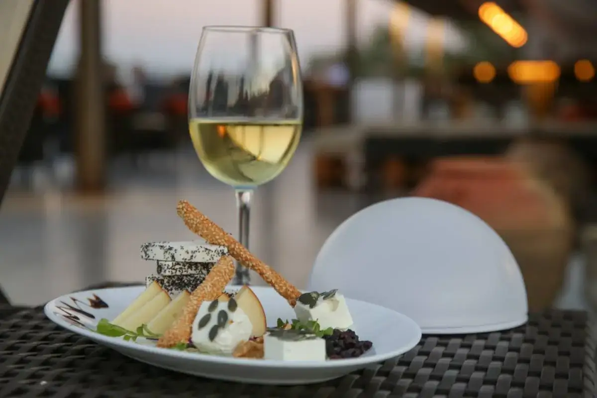 Un verre de Gewurztraminer avec un plateau de fromages et des gressins. Parfait pour savoir que manger avec un Gewurztraminer.