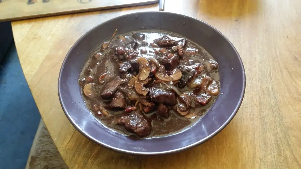 Un plat de bœuf bourguignon mijoté, avec des morceaux de viande tendres et des champignons. Idéal avec un vin rouge corsé.