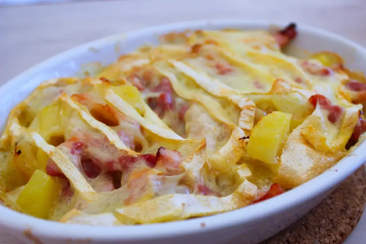 Tartiflette gratinée, un plat savoyard réconfortant. Pour savoir quoi boire avec une tartiflette, pensez aux vins blancs secs ou aux bières légères.