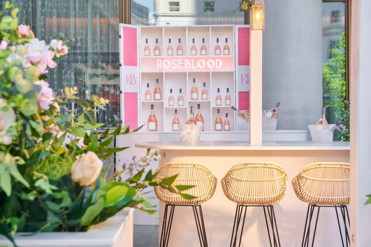 Bar Roseblood avec bouteilles de vin rosé et tabourets en rotin. La température idéale pour le vin rosé est assurée par la glace.