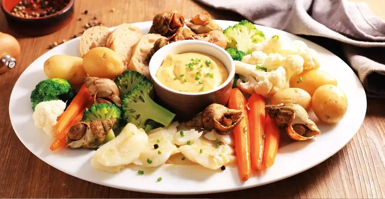 Plateau de fruits de mer et légumes avec un bol d'aïoli crémeux, parfait pour un apéritif convivial.